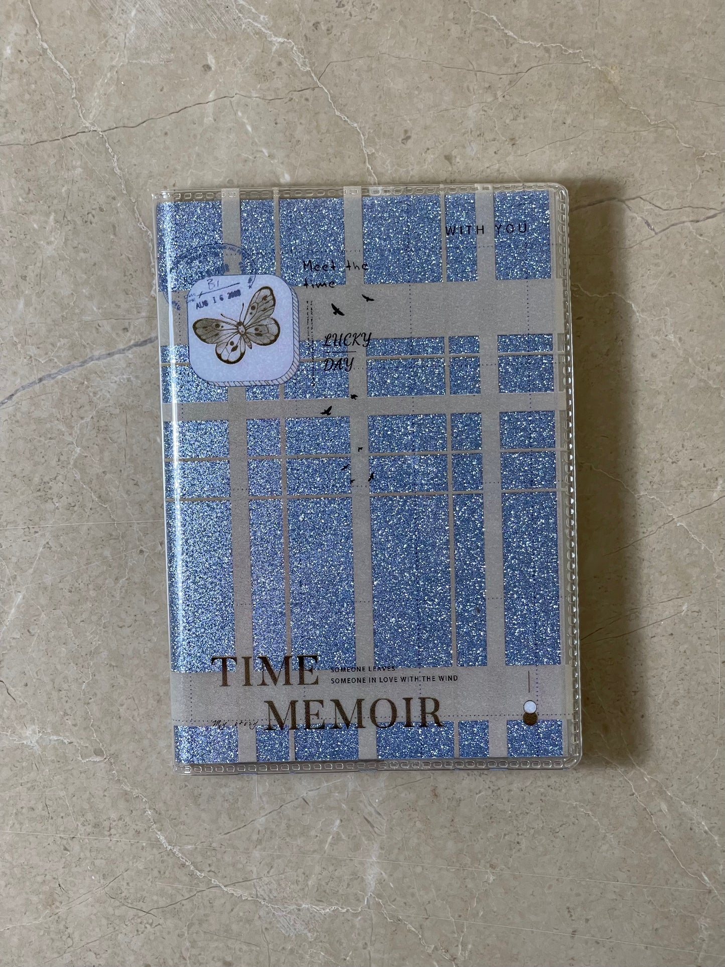 Notebook with blue grid pattern and 'Time Memoir' text on a beige surface