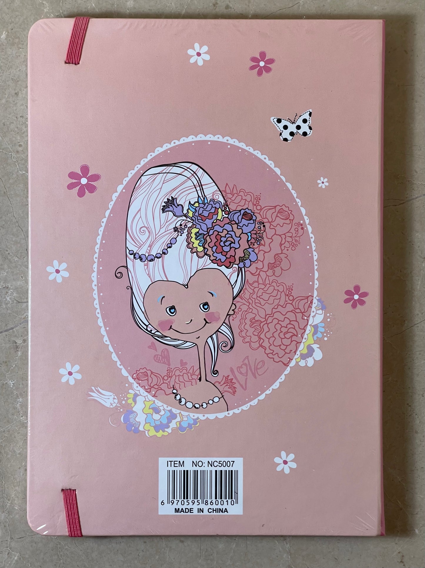 Pink notebook with a cartoon character and floral design on a gray surface