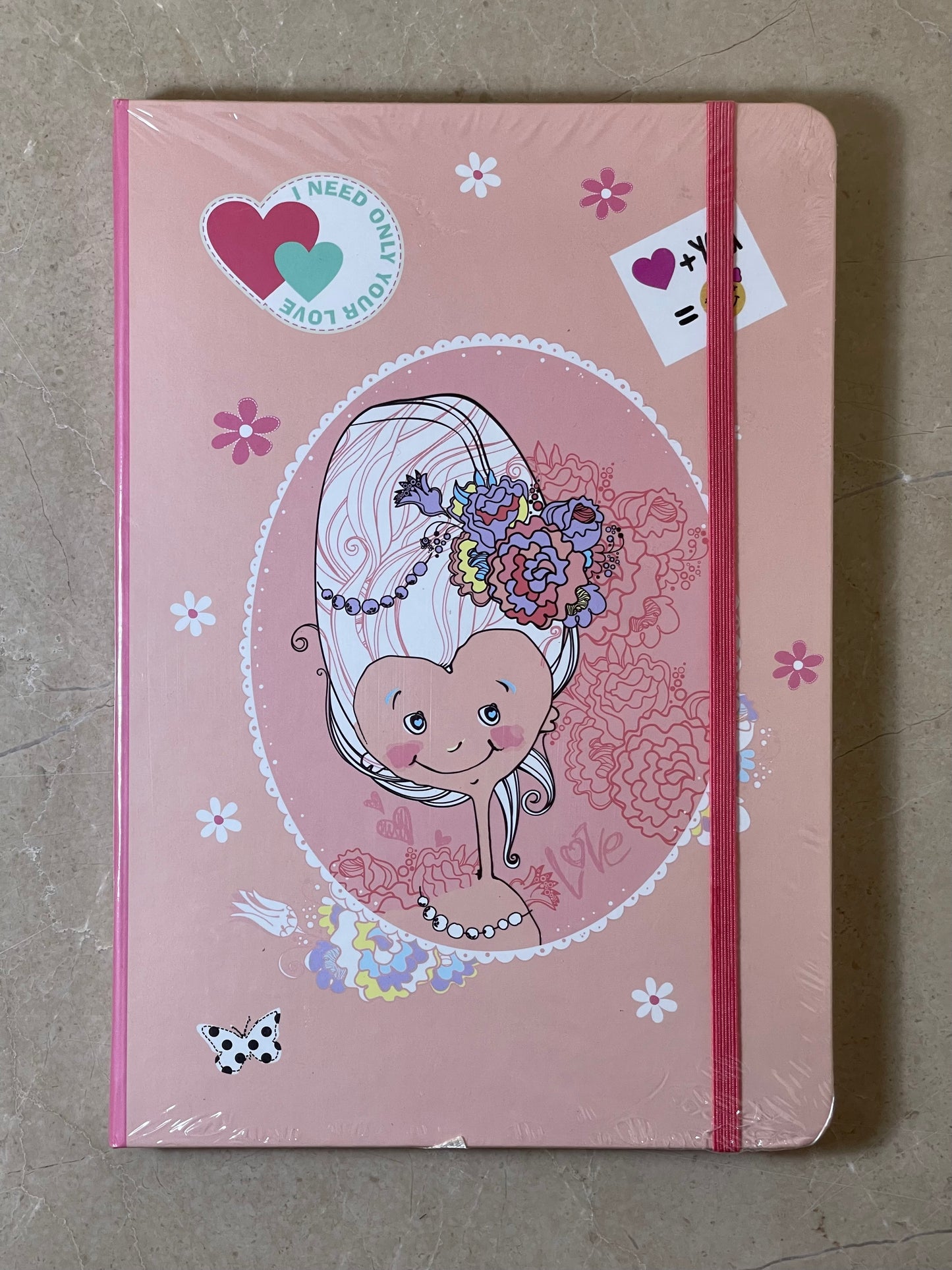 Pink notebook with heart design and stickers on a gray surface
