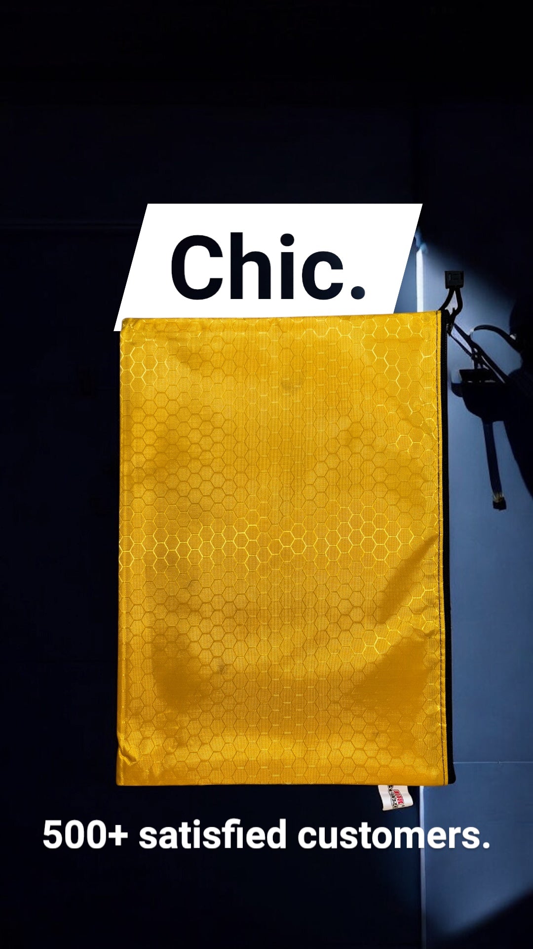 Gold large zipper pouch with 'Chic.' label and text about satisfied customers on a dark background