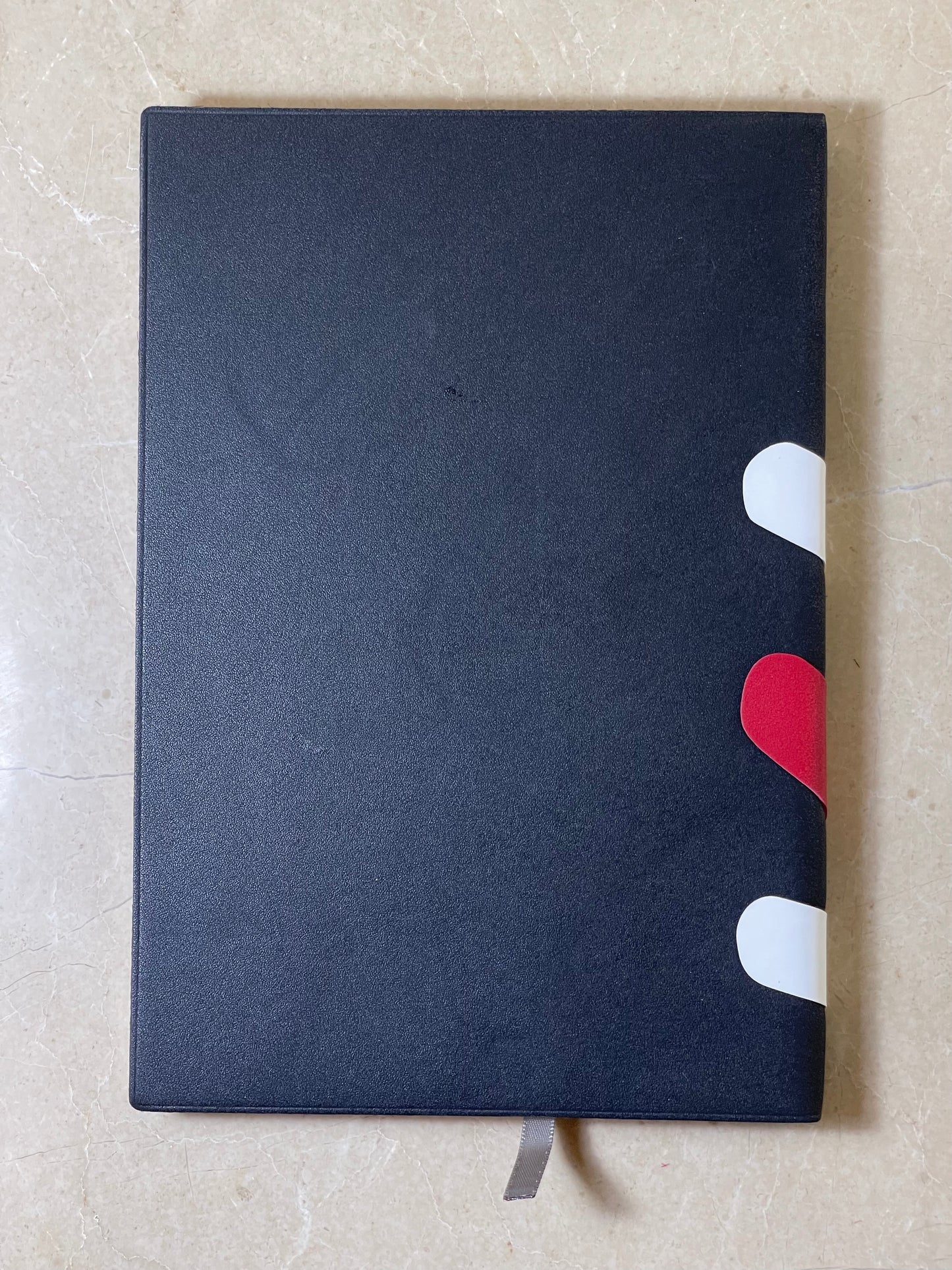 Black notebook with a red and white heart design on a light gray background
