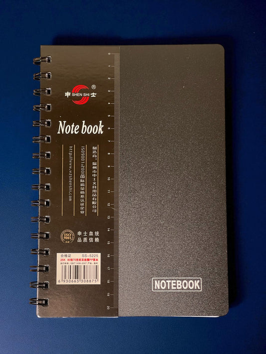 Black spiral notebook with brand logo on a blue background